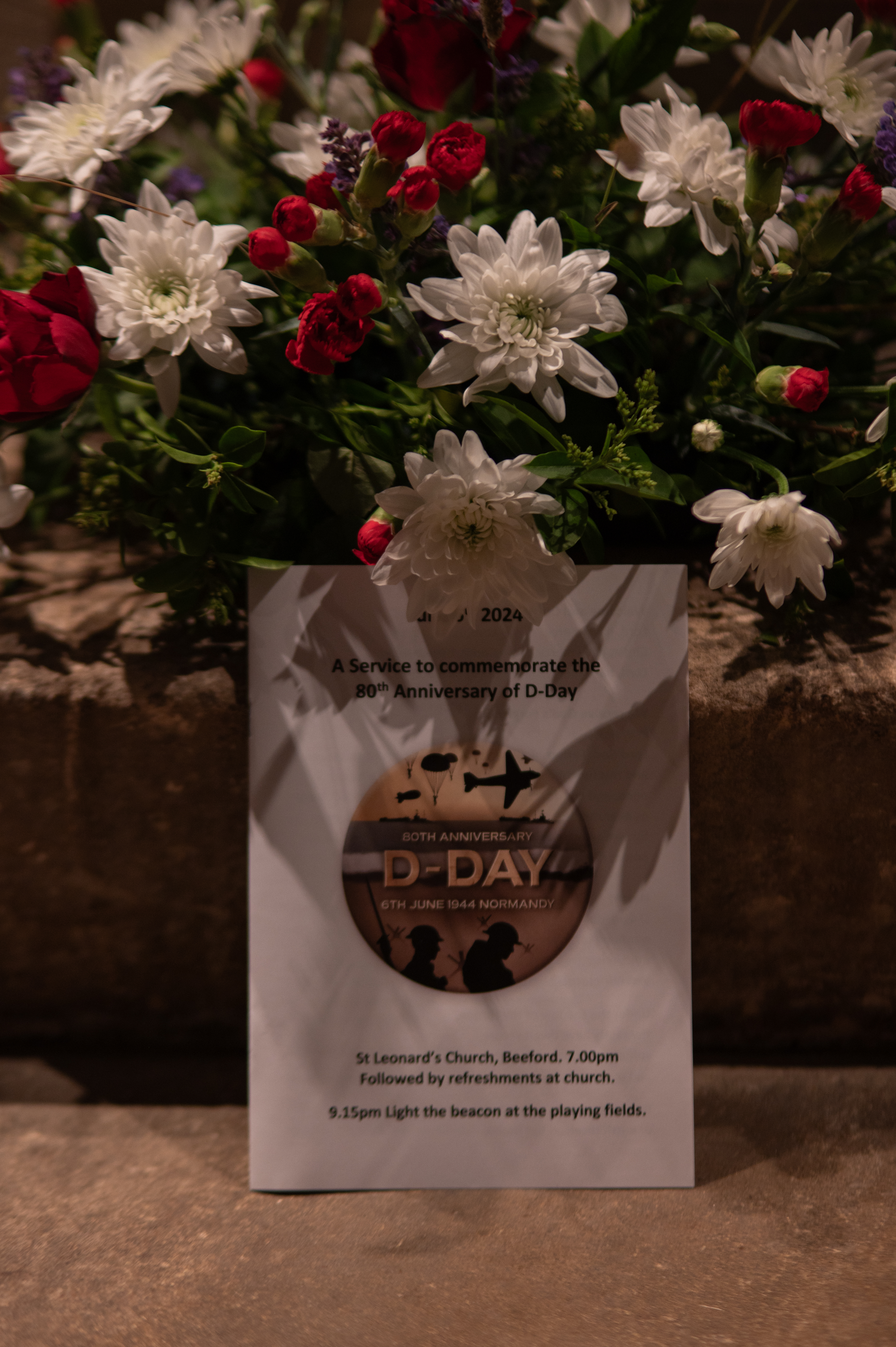 flower display at St Leonards Church with order of service leaflet stood in front of flowers